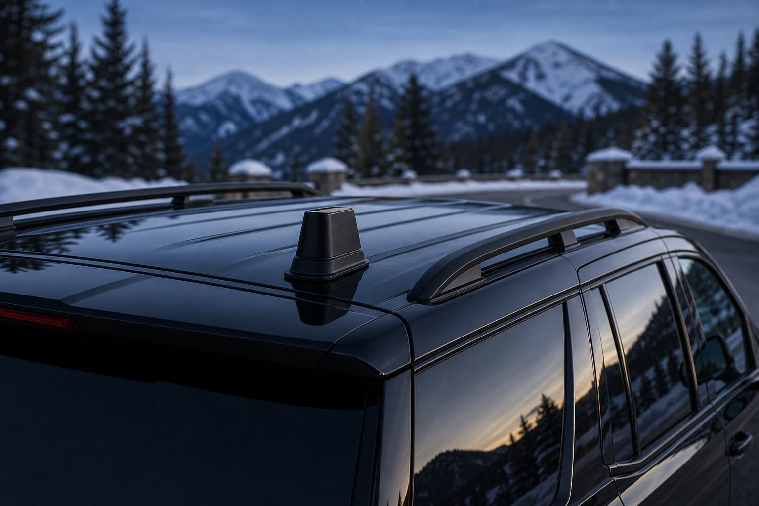 Roof-mounted cellular signal booster antenna on a black SUV against a snowy Rocky Mountain backdrop at dusk.