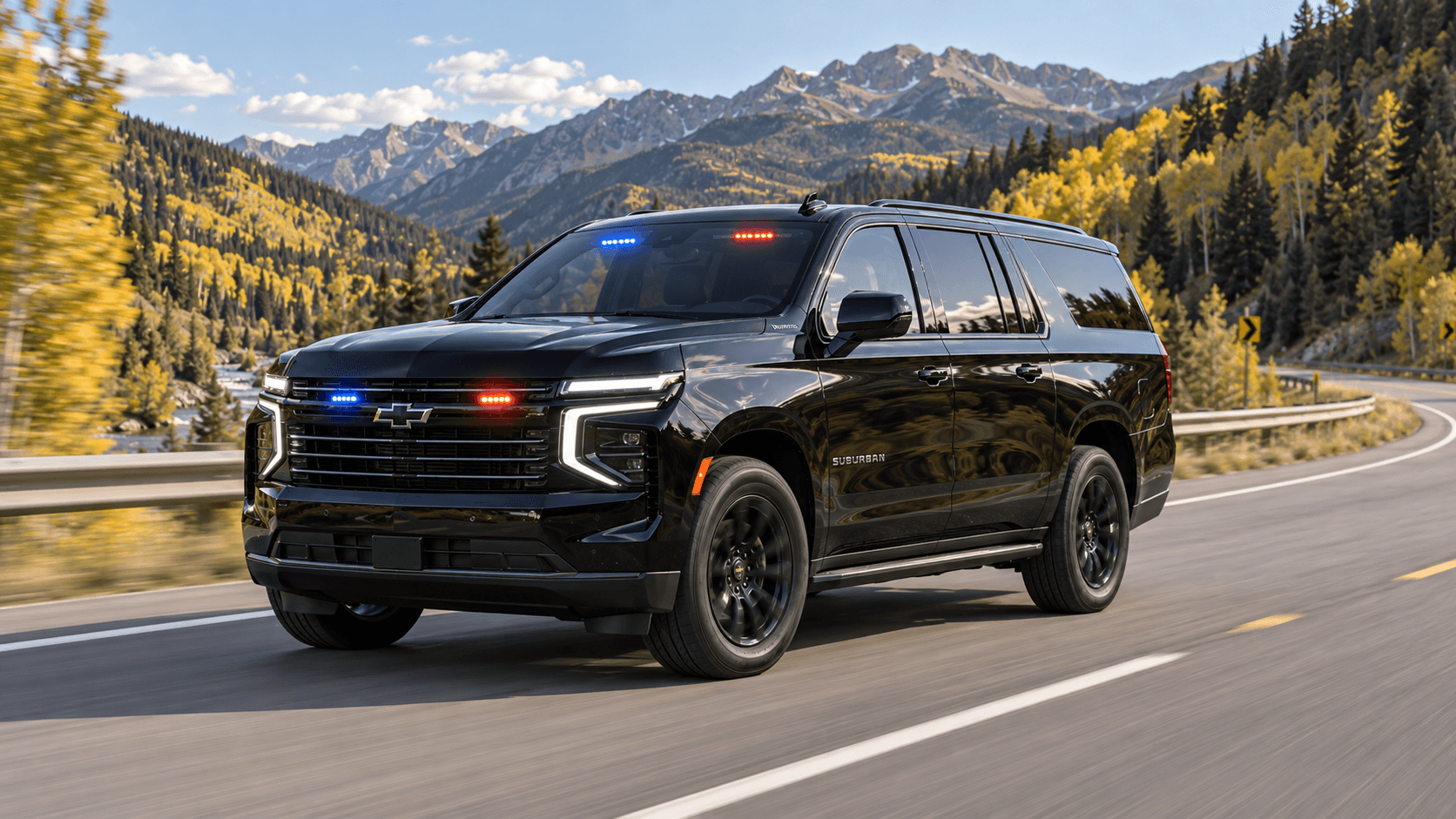 Black SUV with red and blue grille and windshield lights driving a mountain highway through autumn aspens.